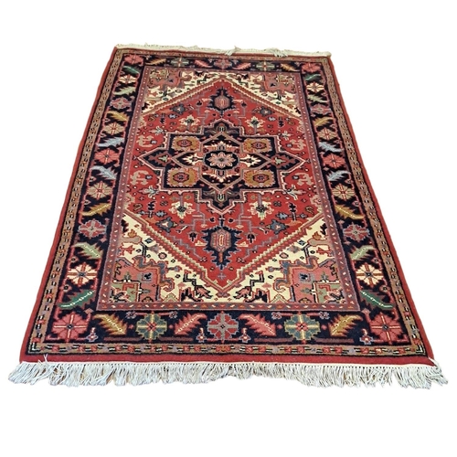 529 - A HERIZ WOOL RUG the wine, indigo and beige ground with central serrated panel filled with stylised ... 