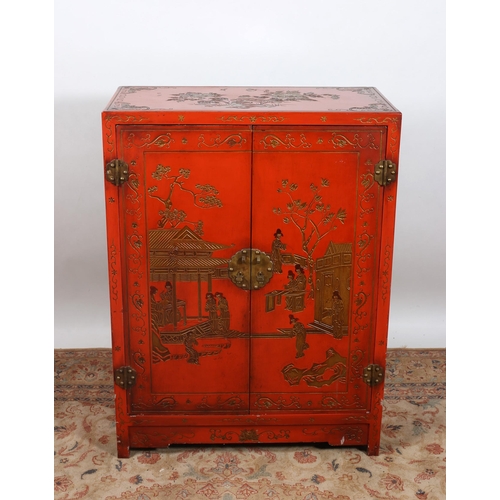 66 - A CHINESE RED LACQUERED CUPBOARD decorated overall with figures, pagodas and foliage the interior wi... 