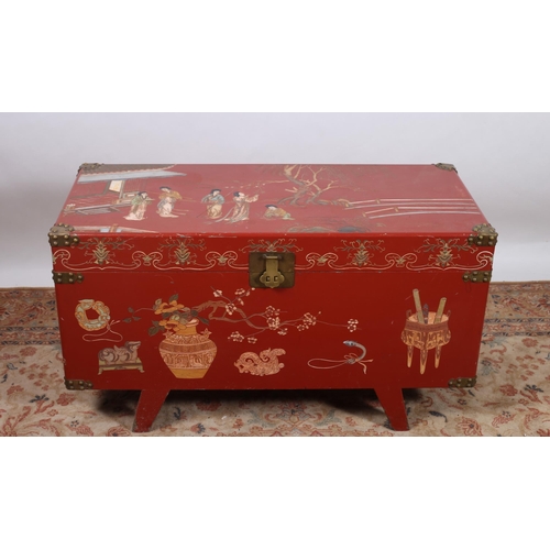 67 - A CHINESE RED LACQUERED AND BRASS BOUND CAMPHOR WOOD TRUNK of rectangular outline decorated overall ... 