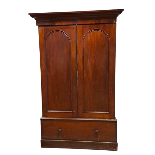 186 - A 19TH CENTURY MAHOGANY WARDROBE the moulded cornice above a pair of panel doors containing hanging ... 