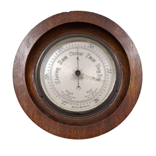 408 - A VINTAGE OAK WALL BAROMETER of cylindrical outline with silvered dial 
27cm (d)