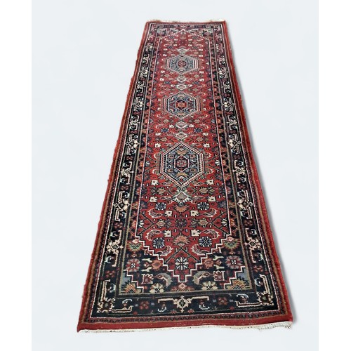 530A - A BIDJAR WOOL RUNNER the wine ground with central panel filled with diamond shaped panels filled wit... 