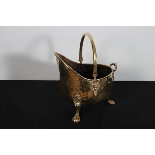 112 - A VINTAGE BRASS SWING HANDLE COAL HELMET raised on claw feet 
40cm (h) x 26cm (w) x 33cm (d)