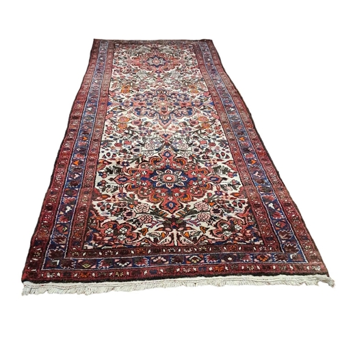 323 - AN ORIENTAL WOOL RUNNER the beige and wine ground with central panel filled with flowerheads and fol... 