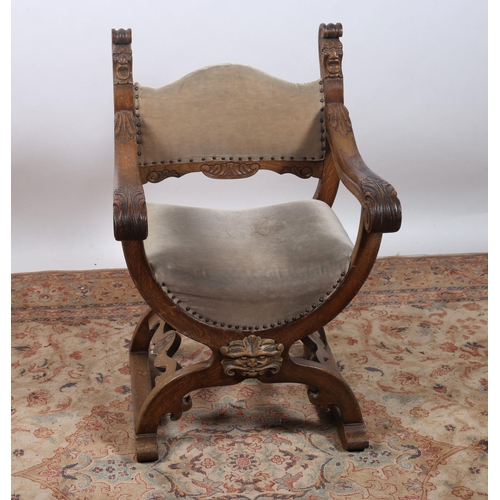 177 - A VINTAGE CARVED OAK ELBOW CHAIR the shaped upholstered back and seat with figural masks with foliat... 