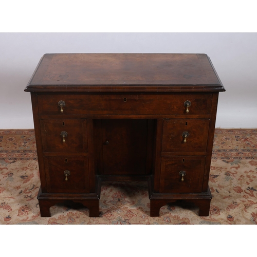 187 - A GEORGIAN STYLE WALNUT CROSSBANDED PEDESTAL DESK of rectangular outline the shaped top with one lon... 