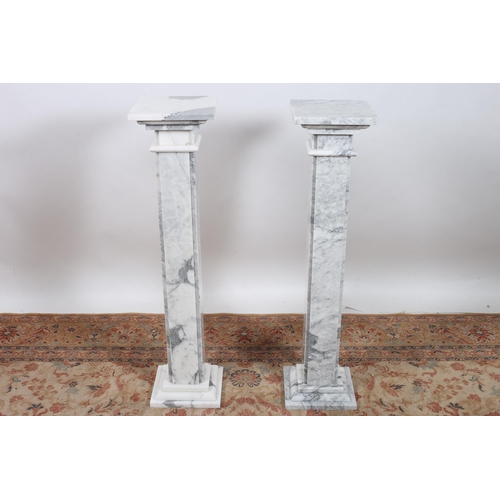 188 - A PAIR OF WHITE VEINED MARBLE PEDESTALS each with a square moulded top with panelled columns on squa... 