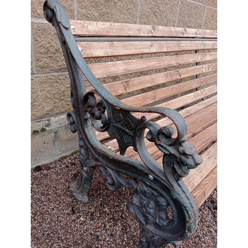 332 - A VICTORIAN STYLE CAST IRON AND PINE GARDEN BENCH the slatted back and shaped seat on pierced foliat... 