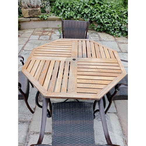 369 - A FIVE PIECE WROUGHT IRON RATTAN AND OAK PATIO SUITE comprising four elbow chairs each with a woven ... 