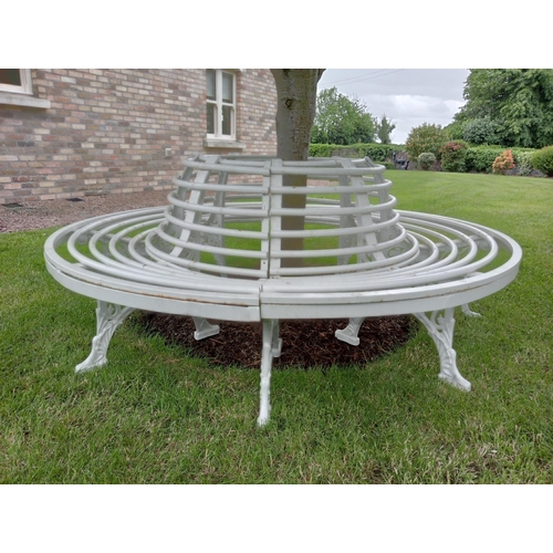 372 - A WROUGHT IRON AND TUBULAR TREE SEAT of cylindrical outline with tubular splats and seat on pierced ... 