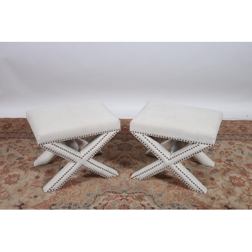 405 - A PAIR OF UPHOLSTERED STOOLS each of rectangular outline the shaped tops raised on X-shaped supports... 