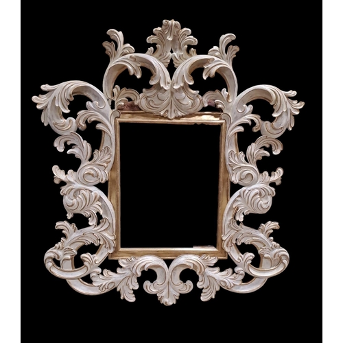 414 - A CONTINENTAL WHITE PAINTED AND GILT MIRROR the rectangular bevelled glass plate within a pierced fo... 