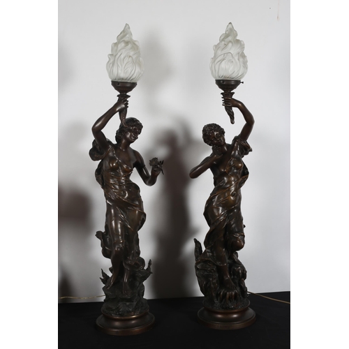 419 - A PAIR OF BRONZED FIGURAL TABLE LAMPS each modelled as a female wearing drapery holding a flame torc... 