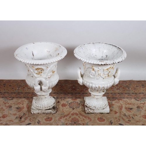 65 - A PAIR OF CAST IRON GARDEN URNS each of semi lobed campana form with loop mask handles above a circu... 