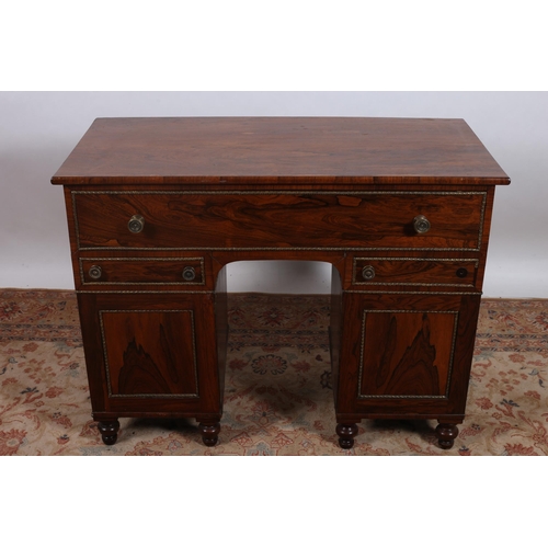 82 - A REGENCY ROSEWOOD AND BRASS DESK of rectangular outline the shaped top above one long drawer with t... 