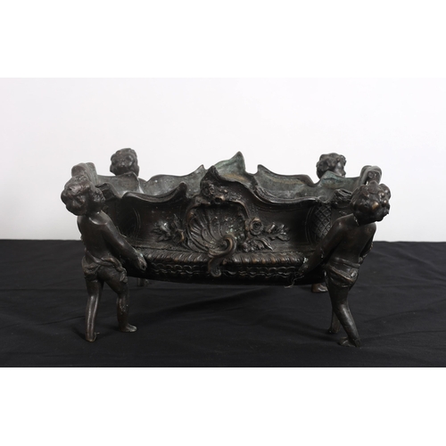 89 - A BRONZE PLANTER of oval outline cast in relief with shells and flowerheads raised on four putti fig... 