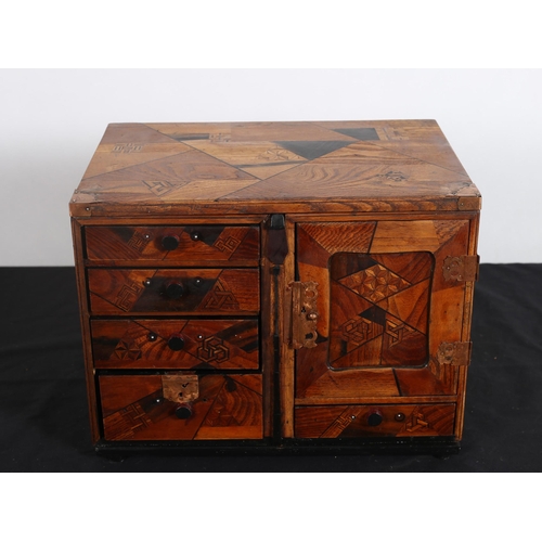 98 - AN ORIENTAL PARQUETRY MINIATURE CHEST of rectangular outline the shaped top above a cupboard contain... 