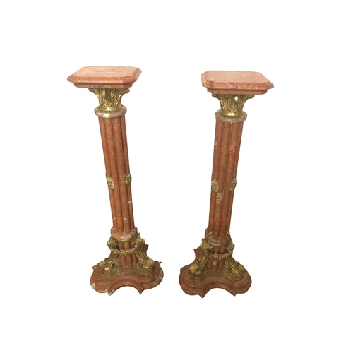 12 - A PAIR OF CONTINENTAL PINK VEINED MARBLE AND GILT BRASS MOUNTED COLUMNS each with a rectangular top ... 