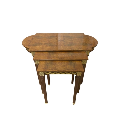 13 - A NEST OF THREE CONTINENTAL WALNUT AND GILT BRASS MOUNTED TABLES the largest of rectangular bowed ou... 