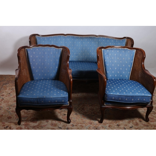 172 - A THREE PIECE HARDWOOD BERGERE SUITE comprising a three seater settee the serpentine top rail above ... 