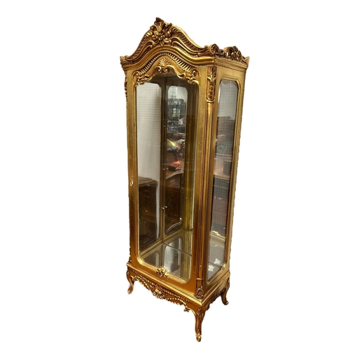 174 - A CONTINENTAL CARVED GILTWOOD CHINA DISPLAY CABINET of rectangular bowed outline the shaped top with... 