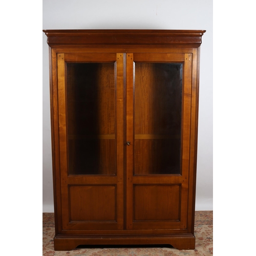 224 - A CHERRYWOOD DISPLAY CABINET the moulded cornice above a pair of bevelled glazed doors containing ad... 