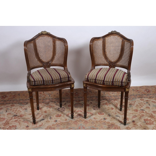 252 - A PAIR OF CONTINENTAL STAINED WOOD GILT BRASS MOUNTED AND CANED SIDE CHAIRS each with a shaped back ... 