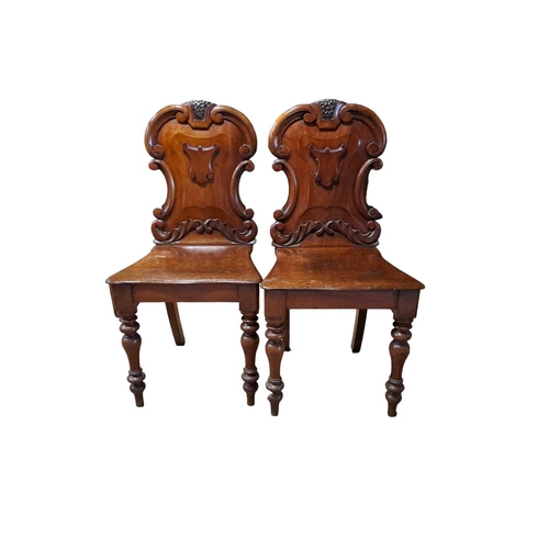 359 - A PAIR OF 19TH CENTURY CARVED MAHOGANY HALL CHAIRS each with armorial scroll carved back with shaped... 