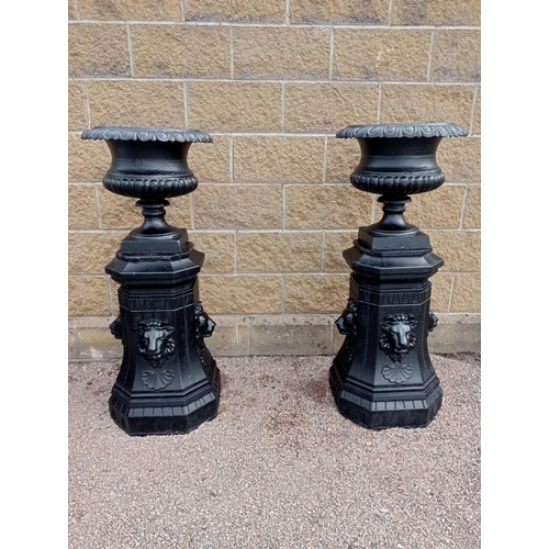 418 - A PAIR OF CAST IRON AND COMPOSITION STONE URNS ON PEDESTALS each of semi lobed campana form on a rec... 