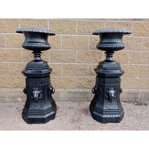 418 - A PAIR OF CAST IRON AND COMPOSITION STONE URNS ON PEDESTALS each of semi lobed campana form on a rec... 