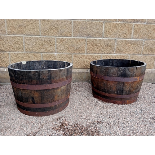 437 - A PAIR OF OAK AND STEEL BOUND BARRELS of cylindrical tapering form 43cm (h) x 64cm (d)