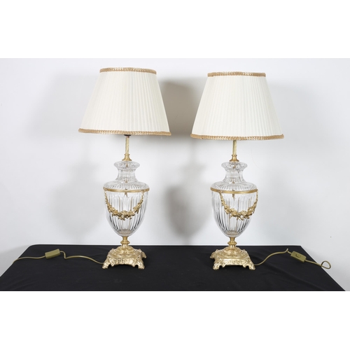 571 - A PAIR OF CONTINENTAL GILT BRASS AND CUT GLASS TABLES LAMPS each of urn form hung with gilt brass fl... 