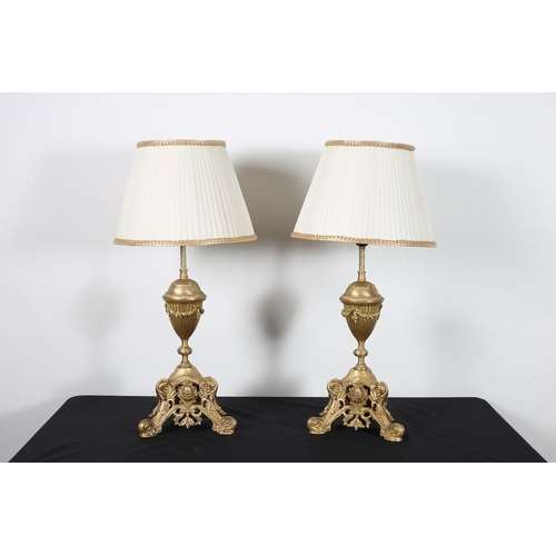 573 - A PAIR OF GILT BRASS TABLE LAMPS each with an urn shaped column hung with floral festoons above a tr... 