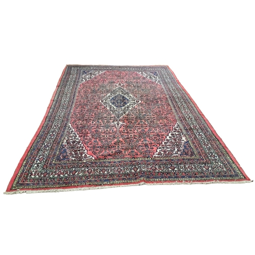 147 - A HERIZ WOOL RUG the light pink ground with central panel filled with stylised flowerheads and folia... 