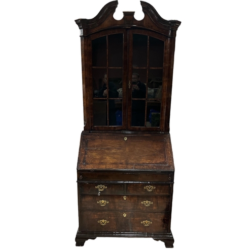 16 - AN EARLY GEORGIAN WALNUT BUREAU BOOKCASE the architectural pediment above a pair of astragal glazed ... 