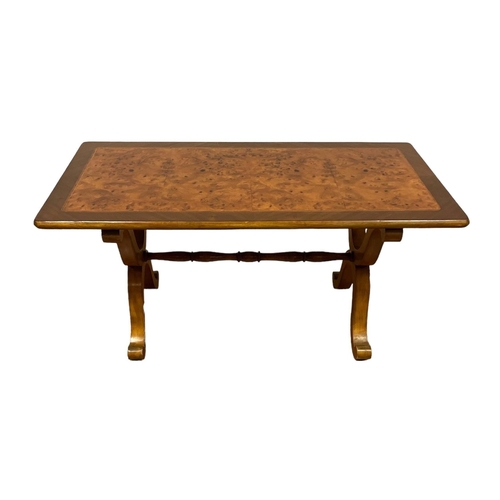 184 - A BURR WALNUT COFFEE TABLE on X-shaped supports with scroll toes joined by a baluster stretcher 50cm... 