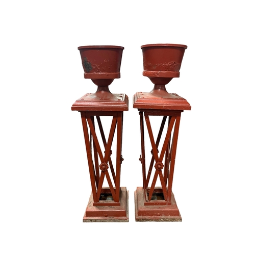 261 - A PAIR OF CAST IRON URNS ON PEDESTALS each of cylindrical tapering form raised on an openwork pedest... 