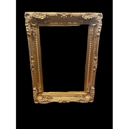 541 - A CARVED WOOD GILT FRAME MIRROR the rectangular bevelled glass plate within a flowerhead and foliate... 