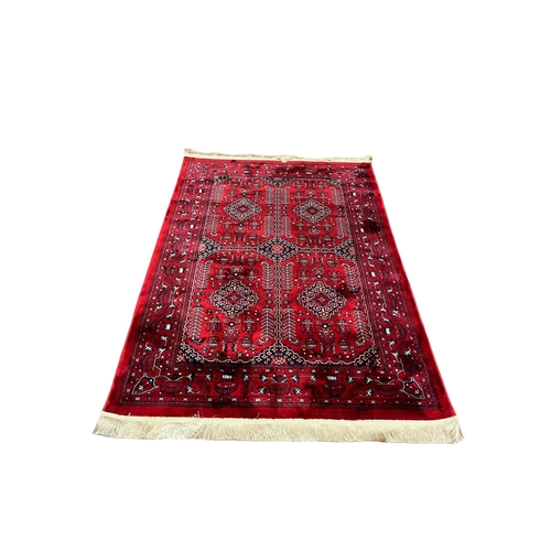 571 - A WINE GROUND PATTERN RUG the central panel filled with serrated panels and hooks with stylised flow... 