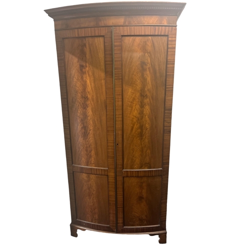 574 - A GEORGIAN STYLE MAHOGANY BOW FRONT WARDROBE containing a hanging rail and shelf on bracket feet 203... 