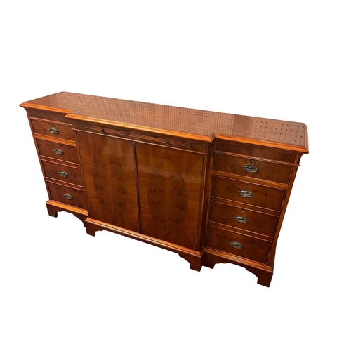 575 - A YEW WOOD SIDEBOARD of rectangular breakfront outline with central cupboard flanked on each side by... 