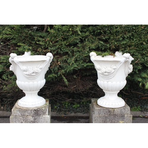 663 - A PAIR OF COMPOSITION STONE GARDEN URNS each of semi lobed campana form with flowerhead decoration a... 