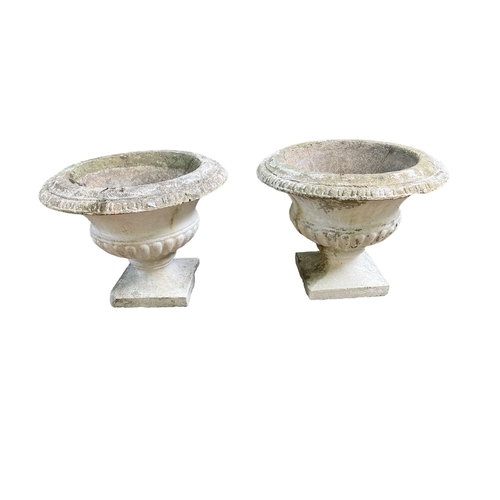 690 - A PAIR OF SANDSTONE GARDEN URNS each of semi lobed campana form on square bases 49cm (h) x 62cm (d)