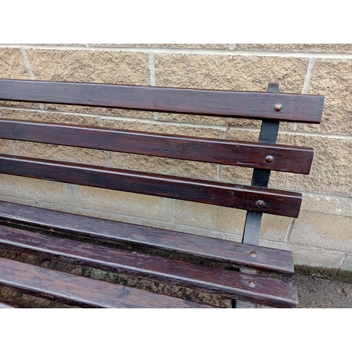 692 - A VICTORIAN CAST IRON AND STAINED WOOD GARDEN BENCH with slatted back and seat inscribed with Latin ... 