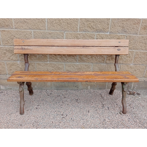 693 - A RUSTIC CAST IRON AND STAINED WOOD BENCH with slatted back and seat on rustic cast iron supports 86... 