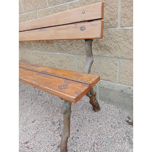 693 - A RUSTIC CAST IRON AND STAINED WOOD BENCH with slatted back and seat on rustic cast iron supports 86... 