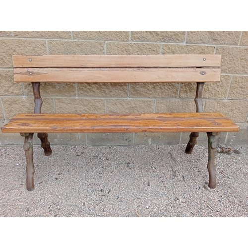 693 - A RUSTIC CAST IRON AND STAINED WOOD BENCH with slatted back and seat on rustic cast iron supports 86... 