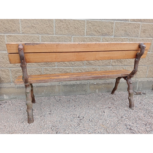 693 - A RUSTIC CAST IRON AND STAINED WOOD BENCH with slatted back and seat on rustic cast iron supports 86... 