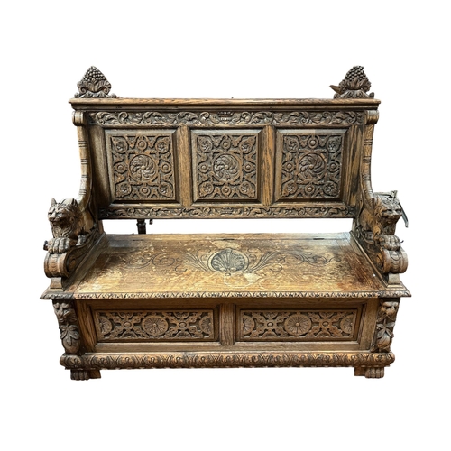 96 - A 19TH CENTURY CARVED OAK MONK'S BENCH with foliate and flowerhead carved panels with hinged seat an... 