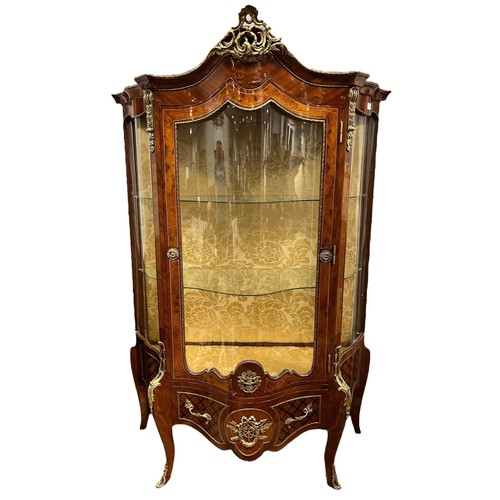 253 - A CONTINENTAL BURR WALNUT KINGWOOD AND GILT BRASS MOUNTED CHINA DISPLAY CABINET of bombe outline wit... 